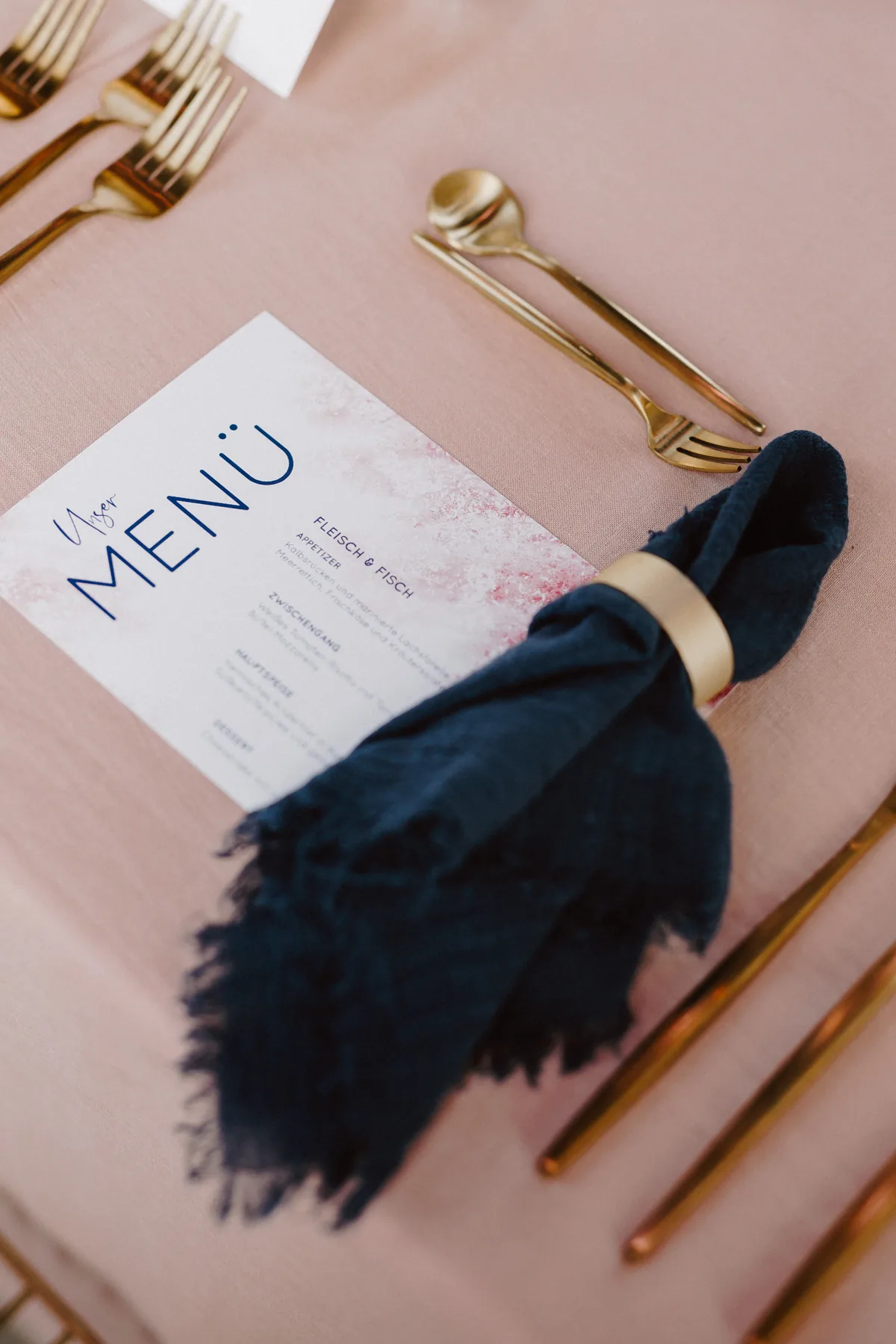 Menükarte in Navy und Rosé neben dunkelblauer Leinenserviette
