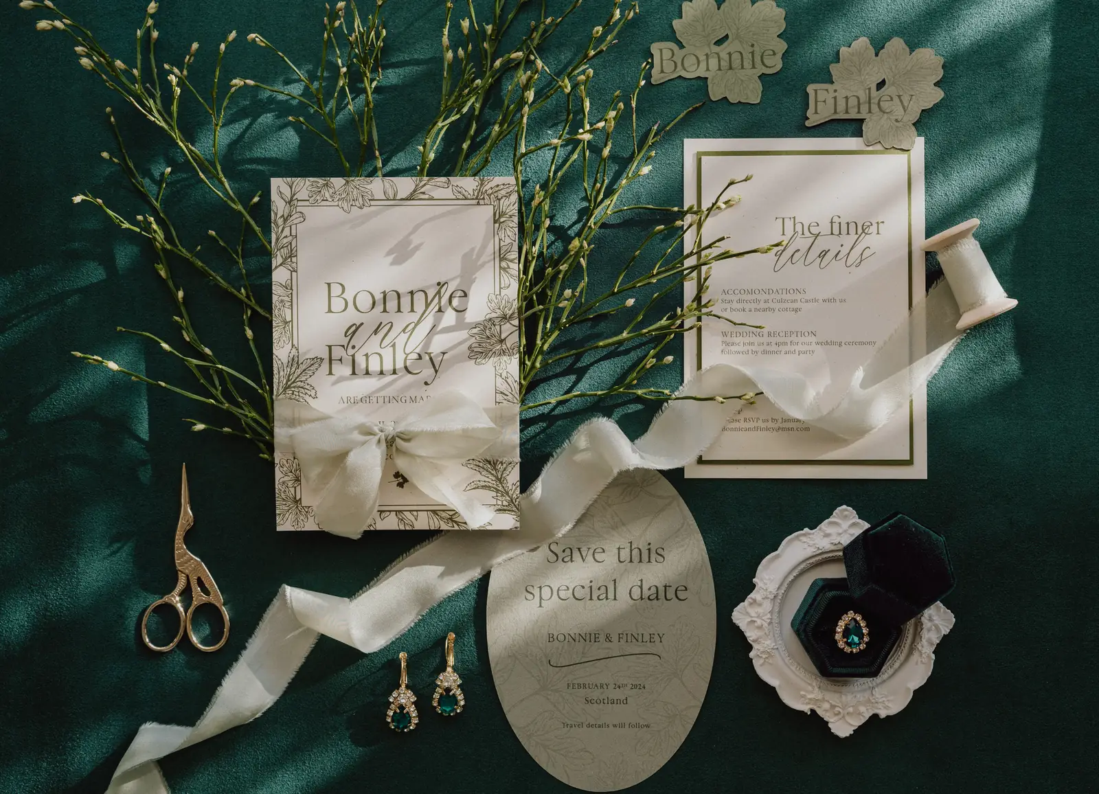 Papeterie-Set für Bonnie und Finley mit ovaler Save the Date, Seidenbändern und Ringbox auf grünem Samt