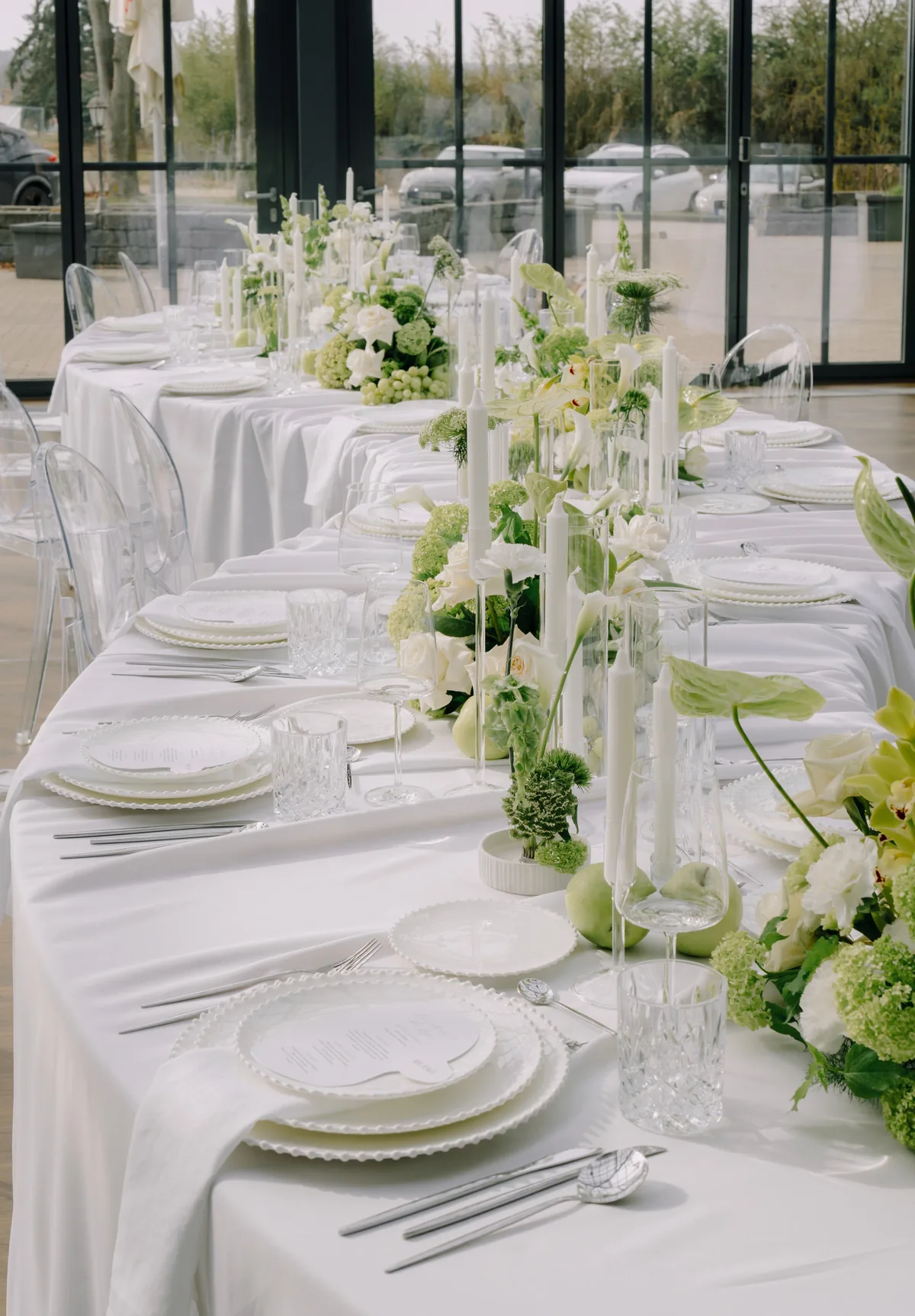 Lange Tafel in der Glashütte mit weißem Gedeck und grüner Floristik