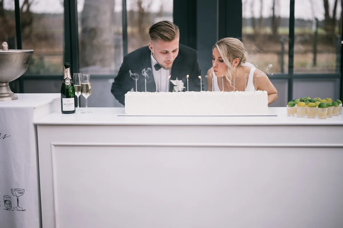 Brautpaar pustet gemeinsam die Kerzen der Hochzeitstorte aus