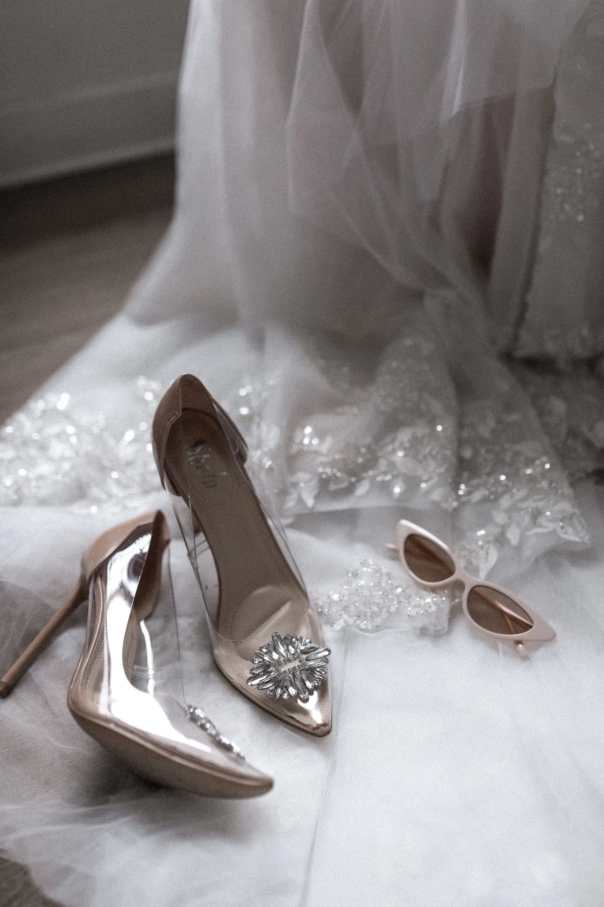 Brautschuhe und rosa Sonnenbrille auf dem Brautkleid